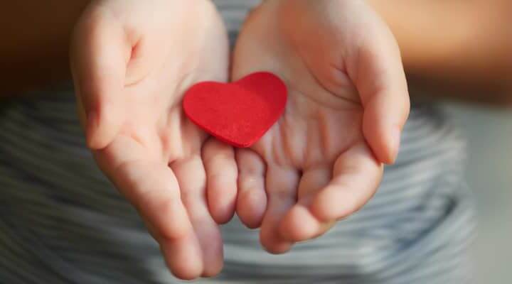 Children holding small red heart in hands