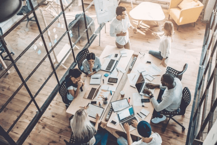 seven people sitting around table working on computers