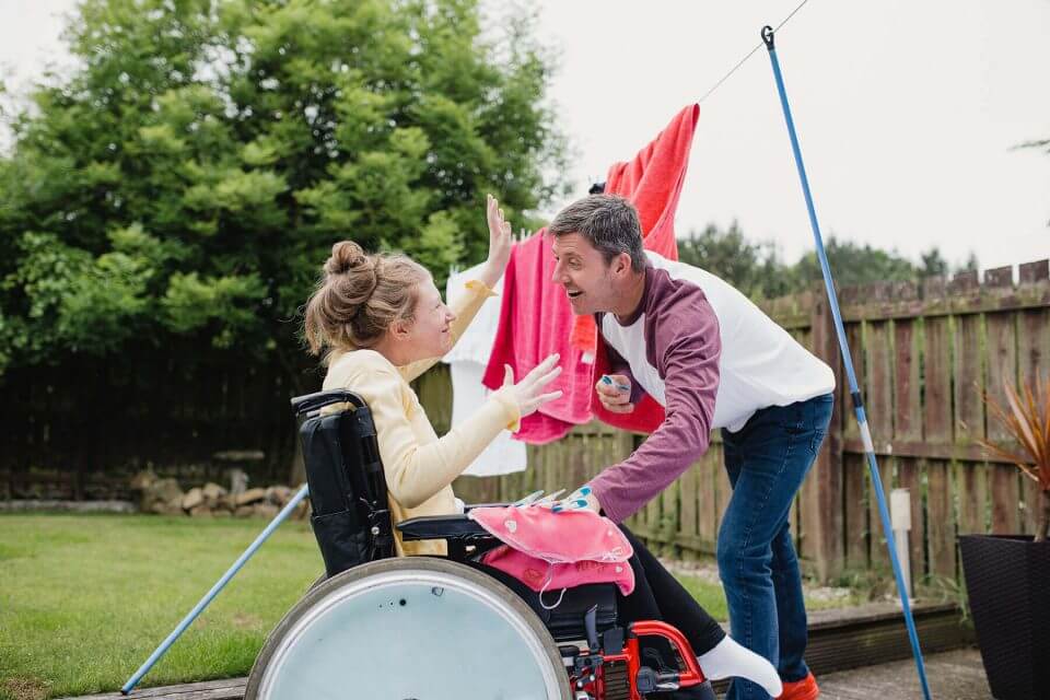 Male helping young woman in wheelchair, hang the washing out