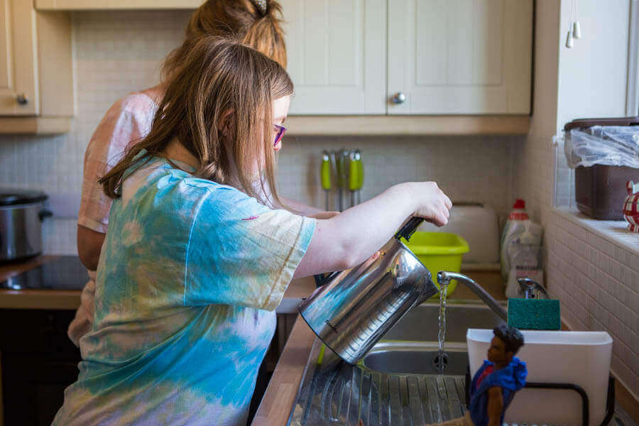 Carer helping supported living resident fill up a kettle