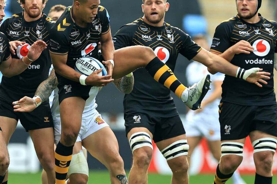 wasps rugby team during a match, with one player jumping and holding the ball