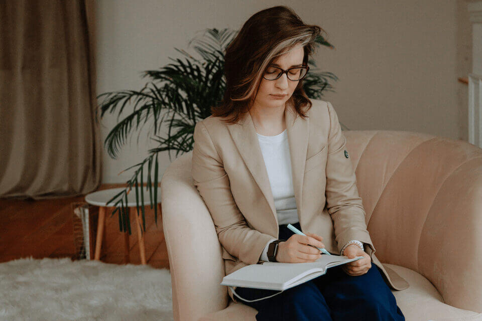 Therapist writing notes while sitting on couch