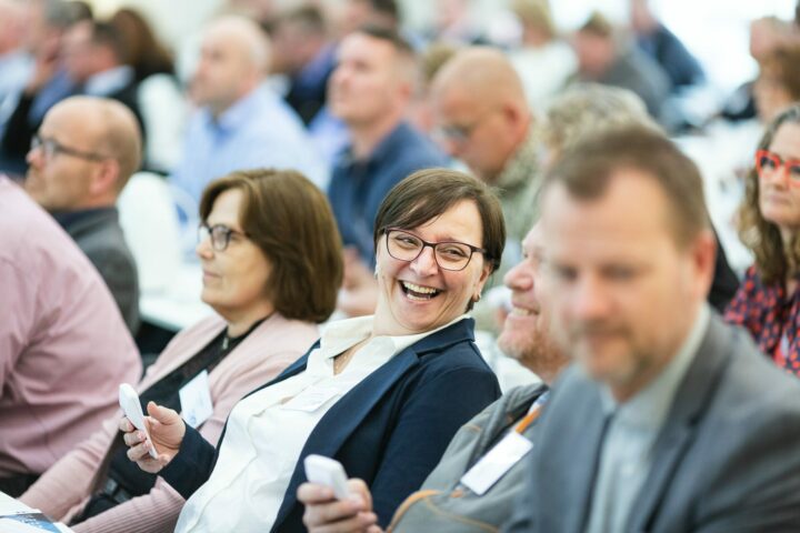 people sitting at a charity event blurred out of focus with one women in focus smiling